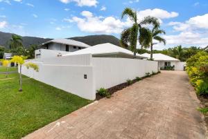 a white house with palm trees and a driveway at The Bird House - Poolside Haven a Stroll from Beach in Palm Cove