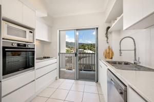 a white kitchen with a sink and a microwave at Trinity Beach Bliss - Experience Tropical Living in Trinity Beach