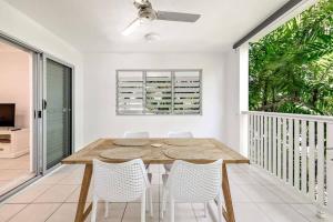 a dining room with a wooden table and white chairs at Trinity Beach Bliss - Experience Tropical Living in Trinity Beach