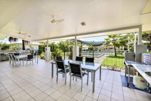 a dining room with tables and chairs and a patio at Trinity Beach Bliss - Experience Tropical Living in Trinity Beach