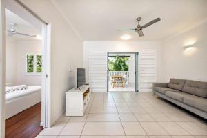 a living room with a couch and a television at Trinity Beach Bliss - Experience Tropical Living in Trinity Beach