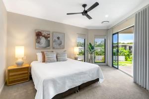 a bedroom with a white bed and a balcony at The Elysian at Argentea - Beachside Stay with Pool in Palm Cove