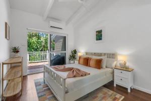 a bedroom with a bed and a large window at Nirvana - Steps to Four Mile Beach with Shared Pool in Port Douglas