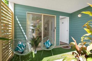 a green house with two chairs on a patio at Wallaby Beach House - Resort-style Comforts in Trinity Beach