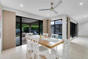 a dining room with a wooden table and white chairs at Trinity Beach Oasis - Poolside Retreat and Serenity in Trinity Beach