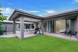 a house with a patio with a green lawn at Trinity Beach Oasis - Poolside Retreat and Serenity in Trinity Beach