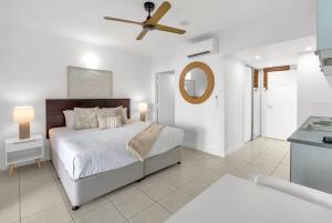 a white bedroom with a bed and a ceiling fan at Lagoon Lookout - Poolside Studio near Trinity Beach in Trinity Beach