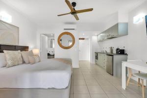 a white bedroom with a bed and a ceiling fan at Lagoon Lookout - Poolside Studio near Trinity Beach in Trinity Beach