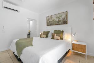 a white bed in a white room with a white bed sidx sidx sidx at Laguna Edge - Swim-Out Studio, near Sea & Dining in Trinity Beach