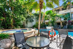 a patio with a table and chairs next to a pool at Escape for Two - A Boutique Tropical Treasure in Port Douglas