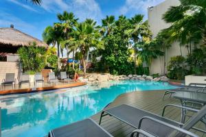 a pool at a resort with chairs and palm trees at Escape for Two - A Boutique Tropical Treasure in Port Douglas +9 photos