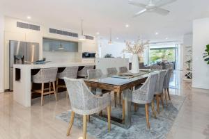 a kitchen and dining room with a wooden table and chairs at Bougainvillea - Beachside Luxury at The Drift in Palm Cove