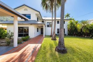 a house with palm trees in front of it at Raphari At The Cove - A Stunning Poolside Escape in Palm Cove