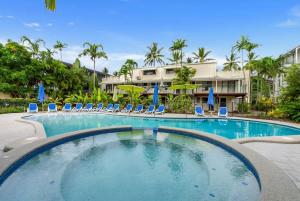 a large swimming pool with chairs and umbrellas at Mira - Poolside Beach Retreat by Four Mile Beach in Port Douglas