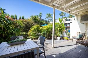 a patio with a white table and chairs and trees at Mira - Poolside Beach Retreat by Four Mile Beach in Port Douglas