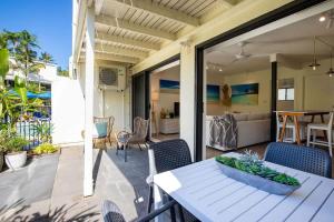 a porch with a white table and chairs on a patio at Mira - Poolside Beach Retreat by Four Mile Beach in Port Douglas