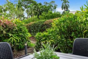 a garden with chairs and plants and trees at Mira - Poolside Beach Retreat by Four Mile Beach in Port Douglas +22 photos