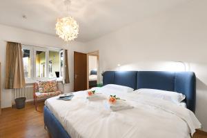 a bedroom with a large bed with a blue headboard at Ca' Lidia - Lugano Villa with Garden and Parking - Happy Rentals in Pregassona