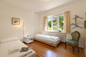 a bedroom with two beds and a chair and a window at Ca' Lidia - Lugano Villa with Garden and Parking - Happy Rentals in Pregassona