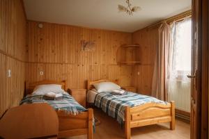 two beds in a room with wooden walls at Guest House Mandrivnyi Rooms&Apartments in Yasinya