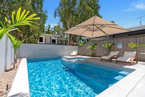 a swimming pool with two chairs and an umbrella at Salt - Beachfront Luxe with Private Pool in Palm Cove
