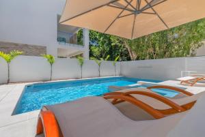 a swimming pool with chairs and an umbrella at Salt - Beachfront Luxe with Private Pool in Palm Cove +41 photos