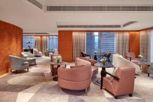a hotel lobby with chairs and tables and windows at Mandarin Oriental, Kuala Lumpur in Kuala Lumpur