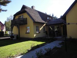 a yellow house with a black roof and a yard at Eiscafe&Pension Schumann in Bresewitz