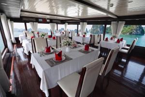 a dining room on a boat with white tables and chairs at Sunlight Legend Cruise in Ha Long