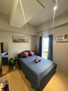 a bedroom with a bed with blue sheets and a window at Studiocuarto Cebu Hub in Mandaue City