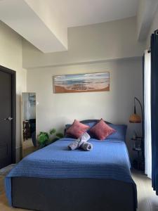 a bedroom with a blue bed with a stuffed animal on it at Studiocuarto Cebu Hub in Mandaue City