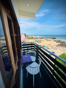 a balcony with a table and chairs and a beach at Serenity Beach Inn in Pondicherry