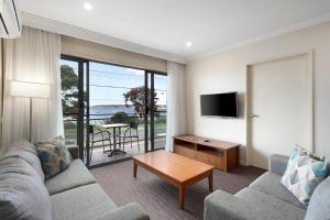 a living room with a couch and a tv and a table at Bayside Geelong Hotel & Apartments, an Ascend Collection Hotel in Geelong