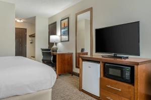 a hotel room with a bed and a flat screen tv at Comfort Inn Manistique in Manistique