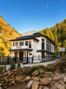 a large white building on a hill with trees at Tiraya Luxury Riverside Hotel & Café in Gushaini