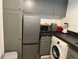 a kitchen with a washing machine and a microwave at Accessible Flat Bedford in Bedford