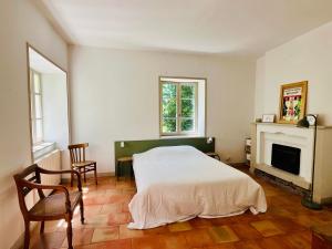 a bedroom with a white bed and a fireplace at Les Cèdres in Valleraugue