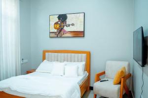 a bedroom with a bed with a guitar and a chair at Ligas homes in Dodoma