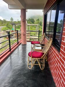 two chairs on a balcony with a view of a farm at Hotel PeaceFul in Bandipur +12 photos