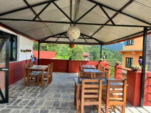 a patio with wooden tables and chairs and a roof at Hotel PeaceFul in Bandipur