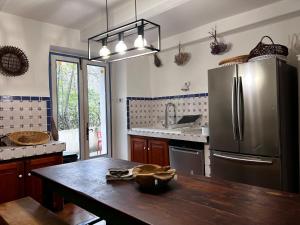 a kitchen with a wooden table and a stainless steel refrigerator at Les Cèdres in Valleraugue +59 photos