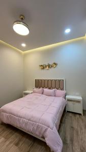 a bedroom with a large pink bed with two tables at استراحه بيت الزلفى in Fulūj Sayghah