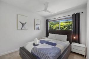 a bedroom with a large bed with a window at Palm Haven Coolum Beach in Coolum Beach +17 photos