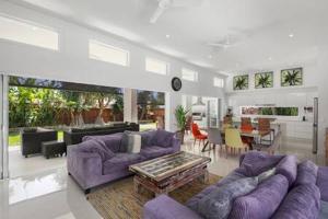 a large living room with purple couches and a table at Palm Haven Coolum Beach in Coolum Beach