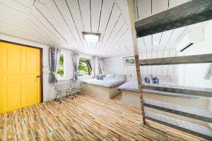 a room with two bunk beds and a yellow door at แฝดสามการ์เด้นท์รีสอร์ท แสมสาร Fadsarm Garden Resort Samaesan in Sattahip