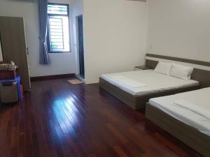a bedroom with two beds and a wooden floor at Nhà nghỉ My Home in Mộc Châu