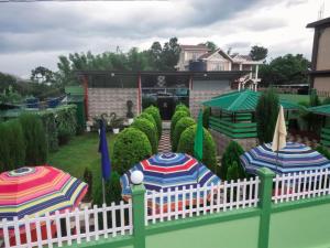 a white fence with umbrellas in a garden at Emmonlang Resort and Restaurant in Dingpasoh