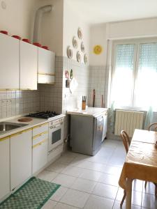una cocina con armarios blancos y una mesa con mesa en Appartamento Roggero, en Levanto
