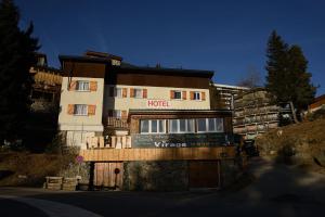 een hotelgebouw met een bord ervoor bij Auberge du Virage in Chamrousse