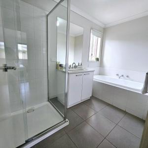 a bathroom with a shower and a sink and a tub at Comfort on Mozart in Shepparton